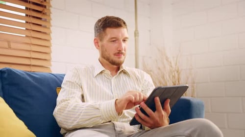 Man Enjoys Tablet on Couch in Bright Home