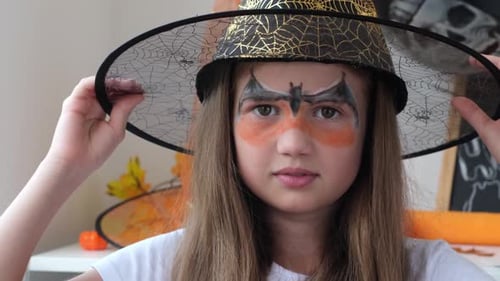 Young Girl Smiling in Witch Hat with Face Paint