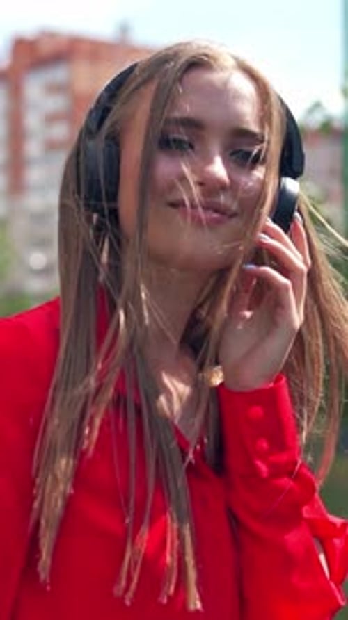 Smiling teenage girl with headphones outdoors.