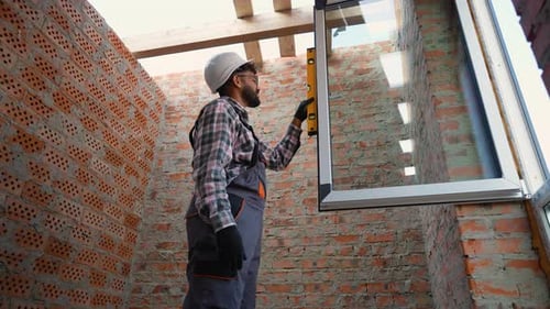 Construction Worker Installing a Window with a Leveling Tool