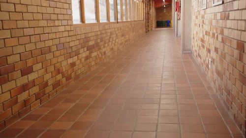 Empty school hallway with brick walls and windows, leading to classrooms, copy space