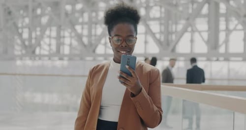 Slow Motion Portrait of Successful Young Businesswoman Using Smartphone Standing in Office Building
