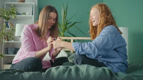 Girlfriends Students Sit at Home on Bed and Paint Nails Two Sisters Having Fun