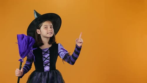 Girl in Witch Costume Smiling and Pointing Upward