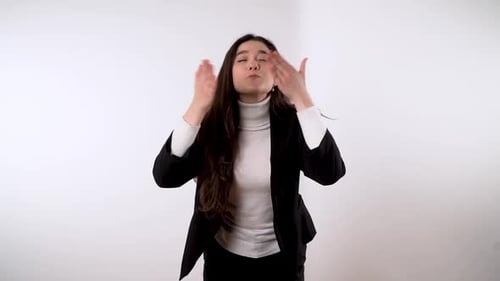 Elegante joven morena enviando besos al aire sobre fondo blanco