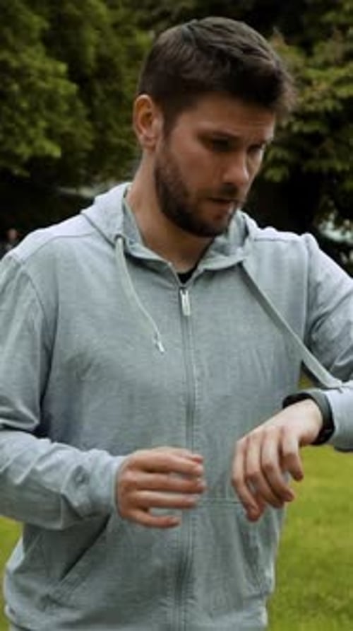 Vertical of Man Running in Forest Woods Training and Look at Smart Watches