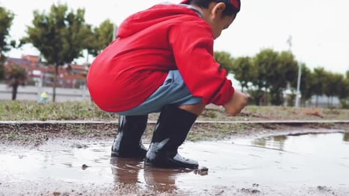 Young Boy Splashing in a Muddy Puddle