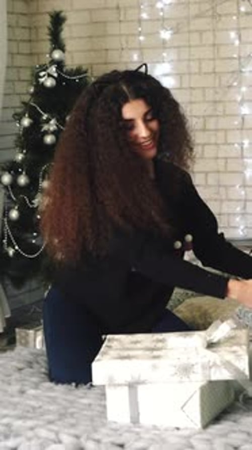 Woman Kneeling with Christmas Gifts by Christmas Tree