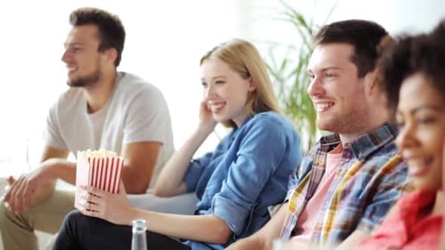 Concept d'amitié, de loisirs, de personnes et de divertissement - Des amis heureux mangeant du pop-corn, buvant