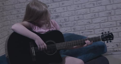 Girl Plays Acoustic Guitar at Home on Sofa