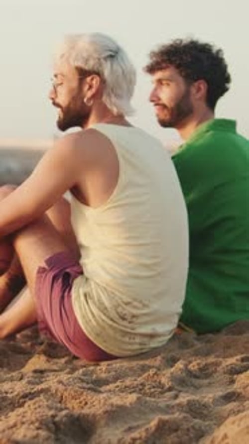 Casal homossexual apaixonado passa tempo juntos sentados na praia com seu cachorro