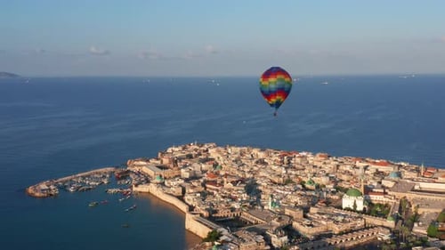 Hot air balloon passing over Acre old city port houses and Mosque at sunrise, Aerial view