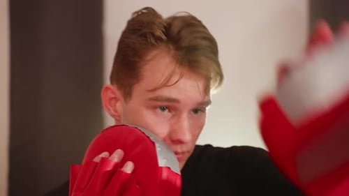 MMA Fighter Holding Red Punching Mitt Close to Face Shows Focus