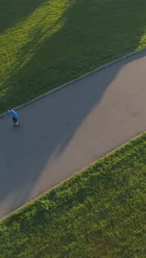 Man is Rollerblading in Green City Park in the Morning Aerial View Drone Fo Vertical Video