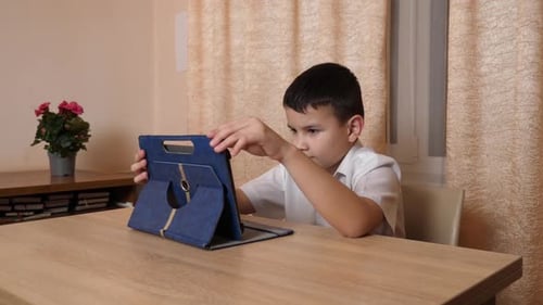 Boy Using Tablet at Table Indoors