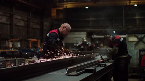 An Industrial Worker is Engaged in Welding Metal Within a Factory Workshop
