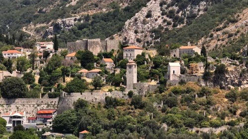 Drone view of the ruins, walls, and clock tower of a fortress on a cliff in the old town of Bar, Mon