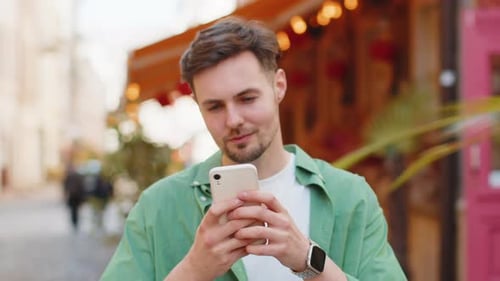 Man Using Phone on City Street Smiling