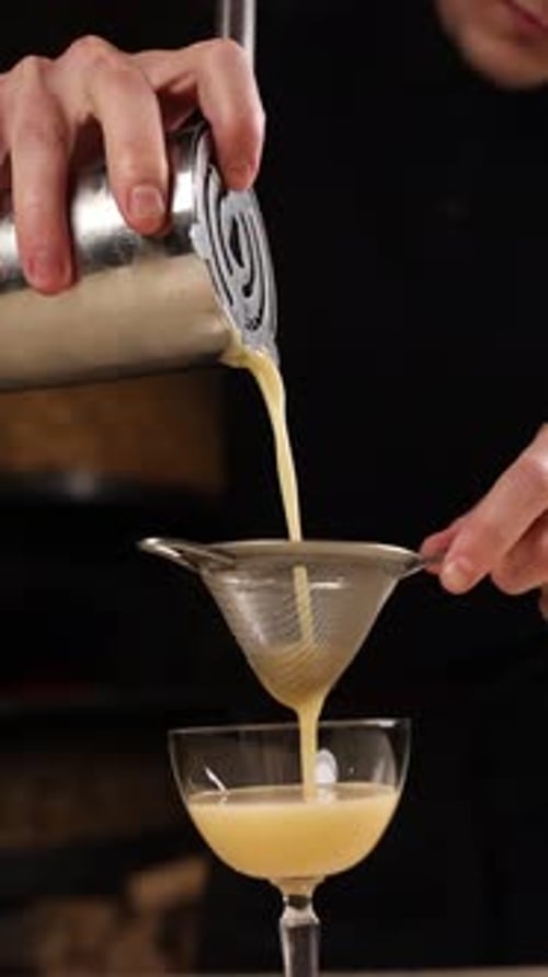 A bartender prepares an alcoholic cocktail . Close-ups