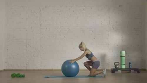 Blonde Woman Stretching with Exercise Ball in Gym