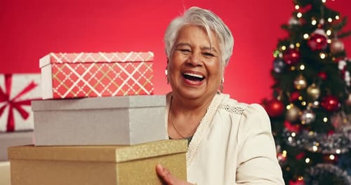 Xmas, face and old woman in studio, gift and laughing with holiday season on red background