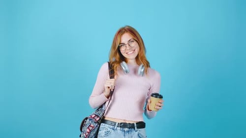 Eine junge Frau mit schicken Kopfhörern und einer Tasse Kaffee posiert anmutig vor einem