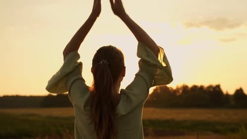 Young Woman Does Yoga in a Field at Sunset