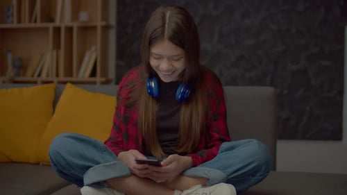 Teen Girl Using Smartphone on Couch at Home