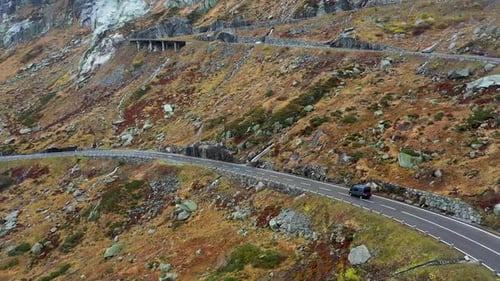 gray camper van driving Grimselpass road in Switzerland in autumn . Aerial view . wet winding road,