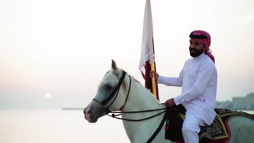 Man Rides White Horse with Flag on Beach