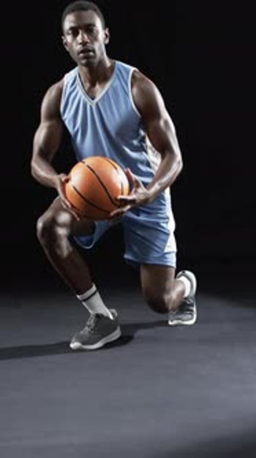 Vídeo vertical: atleta masculino afroamericano posando con baloncesto, fondo negro