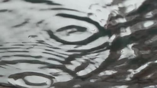 Abstrakte Zeitlupenaufnahme von Regentropfen, die auf Glas landen, von unten gesehen, grauer Himmel