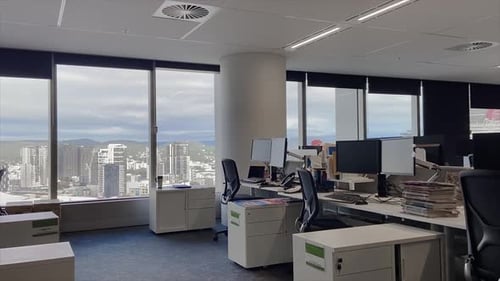 High quality dolly shot over empty desks in a large and deserted office building with unattended wor