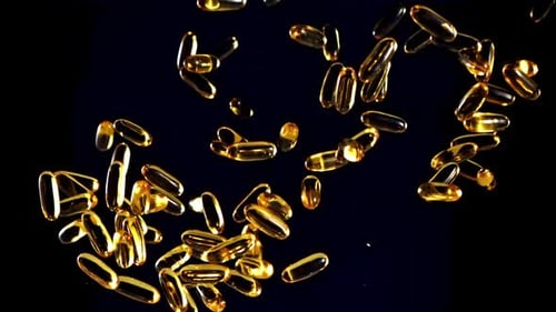 Golden Capsules Falling on Navy Blue Background