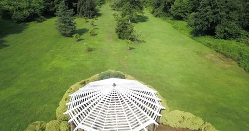 Beautiful white gazebo for weddings in symmetrical green park in aerial view