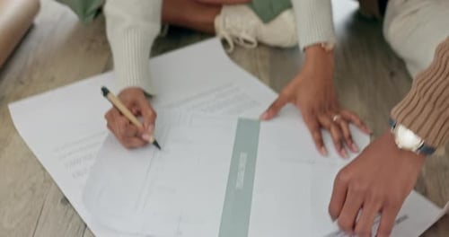 Adults Looking at Building Plans on Wooden Floor