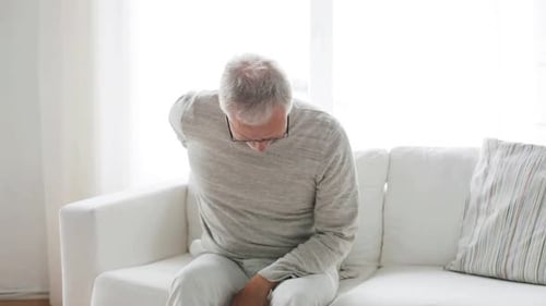 Senior Man Experiencing Lower Back Pain on Sofa