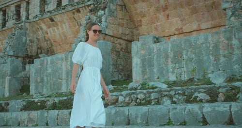 Smiling woman walking near ancient stone Mayan ruins in jungle during Mexico trip