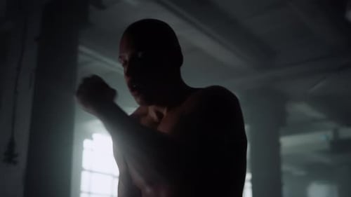 Muscular Boxer Shadow Training in Dark Gym