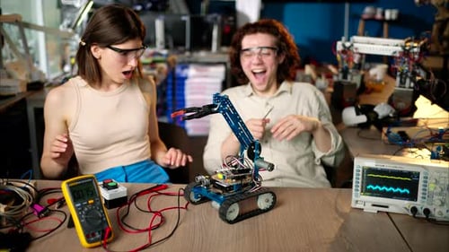 Two young happy engineers fixing a mechanical robot car in the workshop, using VR virtual reality he
