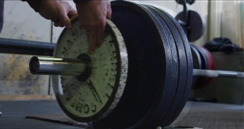 Weightlifter adding plates to deadlift bar