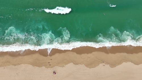 Breathtaking Aerial View of a Pristine Beach and the Waves Gently Rolling on Golden Sand