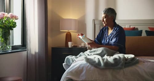 Mature Woman Reading a Book in Bedroom