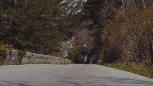 Radfahrer fährt auf einer Bergstraße zwischen hohen Bergwänden