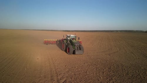 Green tractor works on the field sowing sunflower. Tractor planting corn in Ukraine