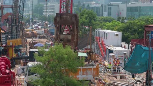At a construction site, engineering workers use a crane to lift and fill an excavation pit with sand