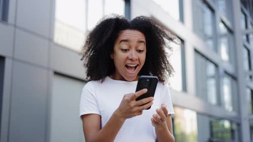 Excited Woman Reacts to Phone News Outside