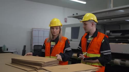 Fabrikarbeiter überprüfen die Kartonqualität in der Produktionsstätte