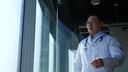 Stressed Doctor Rubbing Head at Modern Hospital