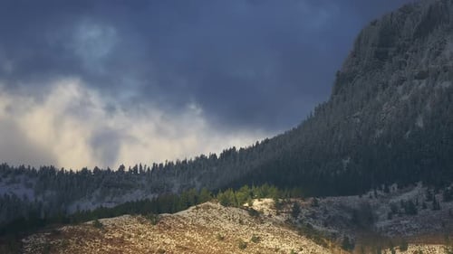 Snow-Covered Forest Mountains Against Sunset With Cloudy Sky. Timelapse